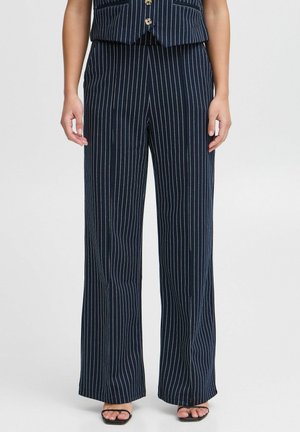 Pantalons larges à rayures marines avec une taille haute, présentant des lignes verticales blanches. Tissu doux avec une texture lisse, fini avec des fentes à l'ourlet.