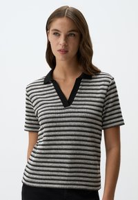Polo shirt a maniche corte a righe con colletto nero e righe orizzontali in bianco e nero. Tessuto a maglia con una vestibilità rilassata.