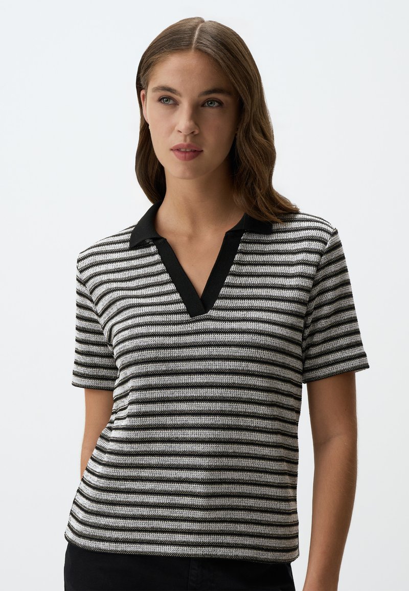 Polo shirt a maniche corte a righe con colletto nero e righe orizzontali in bianco e nero. Tessuto a maglia con una vestibilità rilassata.