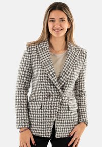 Blazer houndstooth in bianco e nero, tessuto texturizzato, vestibilità su misura, design doppiopetto, rever a punta, con tasche frontali.