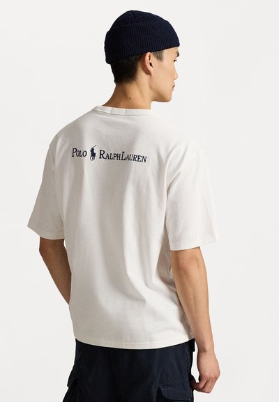 Balts kokvilnas T-krekls ar īsām piedurknēm, ar tumši zilu "Polo Ralph Lauren" logo aizmugurē. Piemērots ikdienas valkāšanai.