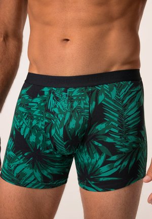 Boxer shorts avec une base noire présentant un motif de feuilles tropicales vertes. Taille élastique, design ajusté et texture de tissu douce.