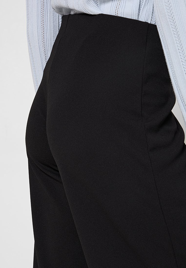 Pantaloni neri a vita alta con una texture di tessuto liscia, caratterizzati da un design a gamba larga e dettagli di cucitura discreti sui lati.