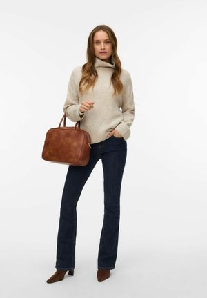 Rjava usnjena torbica z pravokotno obliko, gladko teksturo in dvema ročajema. Model nosi bež pleteno pulover in temno modre zvončaste kavbojke.