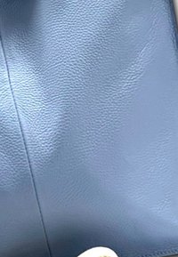 Gestructureerd lichtblauw leer met een licht glanzende afwerking, voorzien van een witte cirkelvormige accent aan de hoek. Eenvoudig en strak ontwerp.