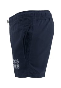 Bañadores de marina con cinturilla elástica, bolsillos laterales y un logo impreso. Fabricados con un tejido ligero, que muestra una textura suave.