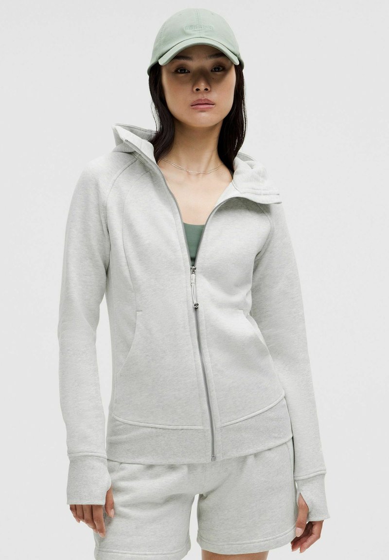 Lys grå zip-up hoodie med hætte, lange ærmer, frontlommer og en tætsiddende design, parret med matchende shorts. Materiale i bomuldsblanding.