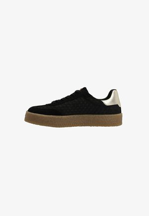 Black suede sneaker with quilted texture, lace-up design, and a contrasting metallic silver heel. Features a thick gum sole.