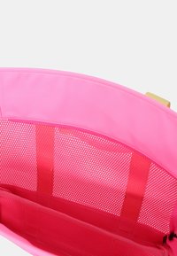 Roze nylon tote bag met gaaspanelen en een soepele textuur. Heeft meerdere compartimenten voor organisatie en een gouden hardware accent.