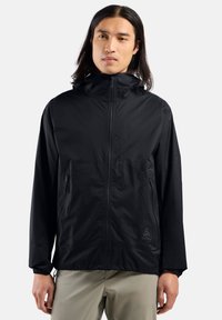 Veste légère noire avec capuche, fermeture éclair à l'avant et poches latérales. Design minimaliste avec des poignets élastiques et un logo discret sur l'ourlet.