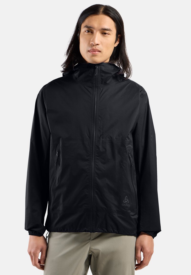 Veste légère noire avec capuche, fermeture éclair à l'avant et poches latérales. Design minimaliste avec des poignets élastiques et un logo discret sur l'ourlet.