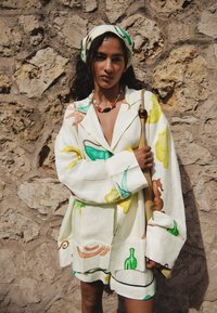 Hvid oversized jakke og shorts sæt med farverige mad-tema prints på linnedstof. Inkluderer et matching hårbånd og perlekæde.