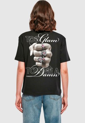 Schwarzes Baumwoll-T-Shirt mit einem Grafikmotiv einer Hand mit Ringen. Der Text lautet "TOO Glam" und "TOO GIVE A Damn" in weißer, geschwungener Schrift.
