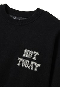 Felpa nera con scollatura a costine e tessuto testurizzato. "NON OGGI" ricamato in bianco sul petto con un carattere audace.