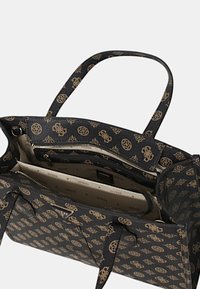 Sac fourre-tout noir avec impression du logo doré, deux poignées et fermeture éclair. L'intérieur comporte plusieurs compartiments et une doublure à motifs.