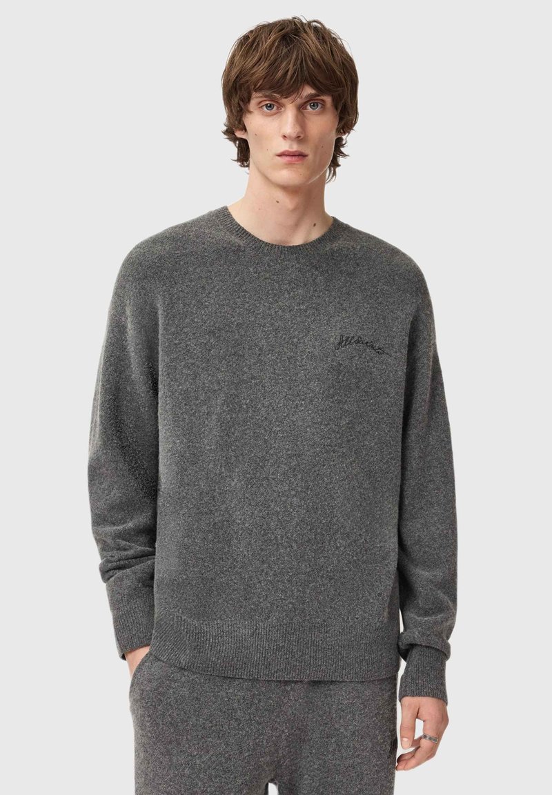 Grauer Strickpullover mit Rundhalsausschnitt und gerippten Bündchen. Verfügt über ein dezentes, aufgesticktes Branding auf der Brust. Weiche Textur, lockere Passform.