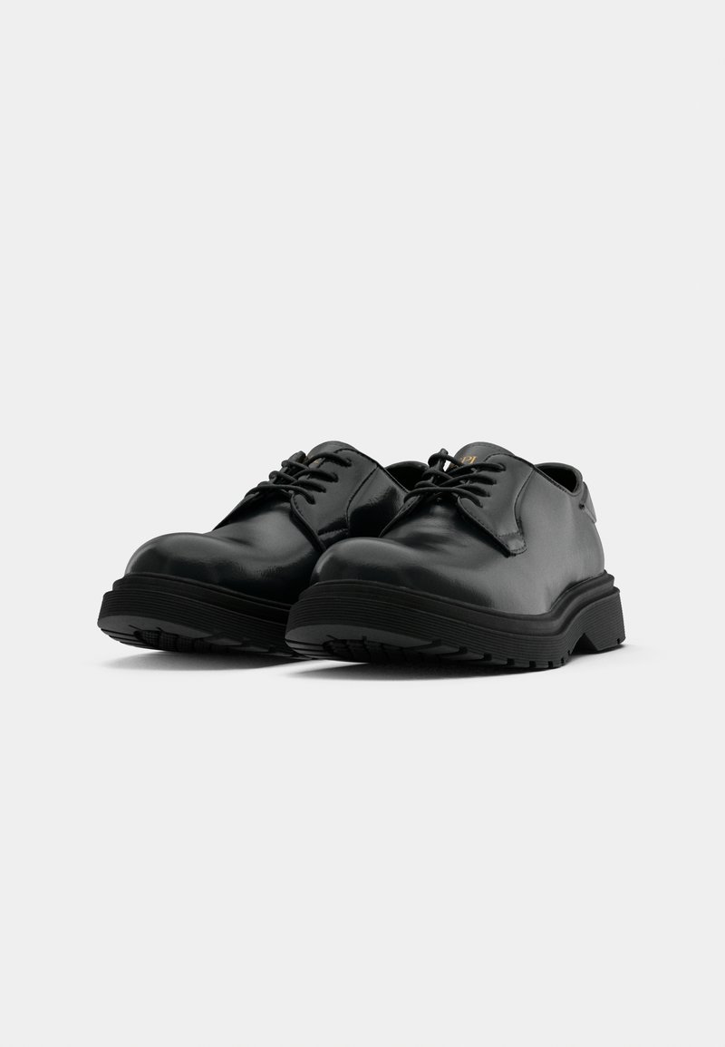 Zapatos de cuero negro con cordones, punteras redondeadas, suelas de goma negra texturizada y un diseño minimalista. Presenta un logotipo en relieve en la lengüeta.