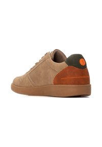 Zapatilla de gamuza beige con detalles en marrón y naranja, punta redondeada, diseño con cordones, suela de goma y detalle del logo en el talón.