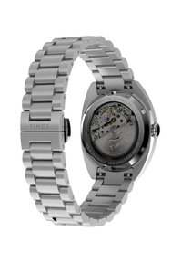 Ασημένιο ρολόι Timex από ανοξείδωτο ατσάλι με μπρασελέ από μεταλλικούς κρίκους, ανοιχτή πλάτη κάσας που αποκαλύπτει τον αυτόματο μηχανισμό και τα εσωτερικά γρανάζια.