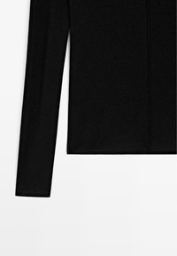 Maglietta nera a maniche lunghe realizzata in un tessuto morbido. Presenta un design senza cuciture e un orlo dritto, con una finitura minimalista e testurizzata.