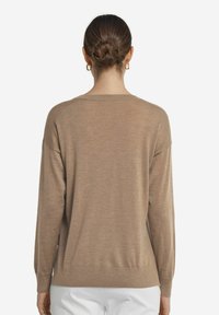 Beige stickad tröja, rundad hals, långa ärmar, ribbade muddar och nederkant, lättviktig, mjuk textur, avslappnad passform, minimal detaljering.