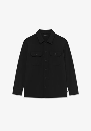 Zwart overhemd met lange mouwen, knoopsluiting, kraag en twee voorzakken met klep en knoop, plat uitgestald op een witte achtergrond.