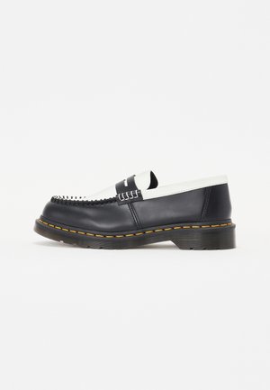 Pantof de piele neagră, tip slip-on, cu un accent din piele albă. Prezintă cusături decorative și o talpă din cauciuc cu margine galbenă. Design cu vârf rotunjit.