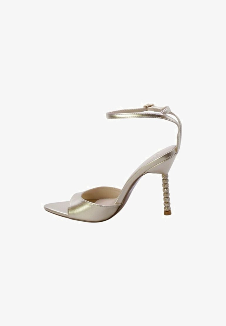 Sandaletta alta in metallo dorato con punta quadrata, cinturino per la caviglia e tacco decorativo ricoperto di cristalli. Texture liscia, design minimalista.