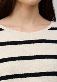 Pullover-Sweater mit beigem Grundton und schwarzen horizontalen Streifen, weitem Ausschnitt und strukturiertem Strickstoff.