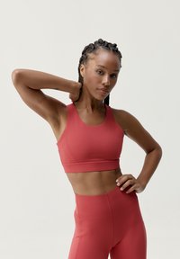 Sportbh och högmidjade leggings i ett matt, djuprött tyg. Bh:n har breda band, en rundad halsringning och en stödjande passform.