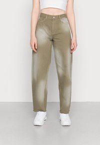 Khaki wijde jeans met een vervaagde afwerking, met twee voorzakken en een tailleband met een knoopsluiting. Gecombineerd met witte sneakers.