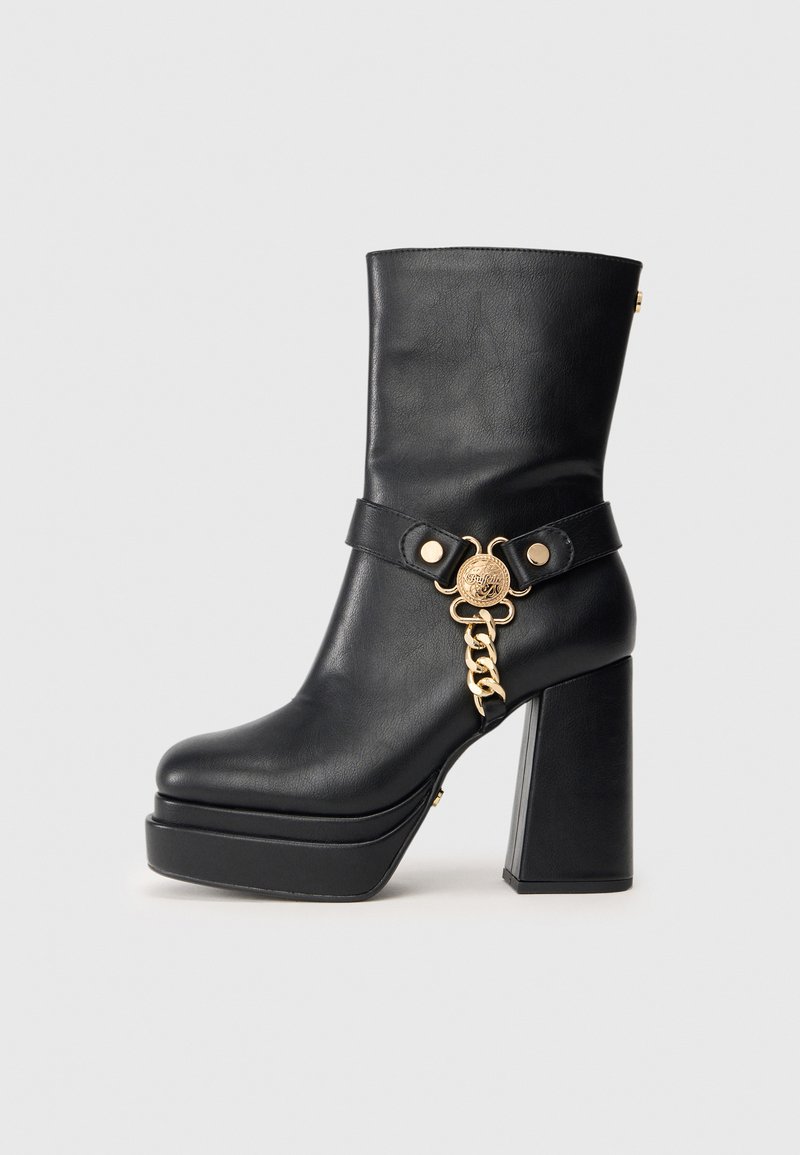 Fekete bőr platform bokacsizma, tömbsarkal, arany lánccal és díszes medál részlettel az oldalon.