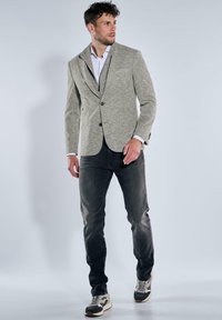 Gray textured blazer with black trim, single button front, paired with dark jeans and sneakers. White shirt underneath adds contrast.
