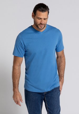 Royalblauwe T-shirt met korte mouwen en V-hals, gemaakt van zachte stof, gecombineerd met blauwe jeans. De pasvorm is ontspannen, wat het casual ontwerp benadrukt.