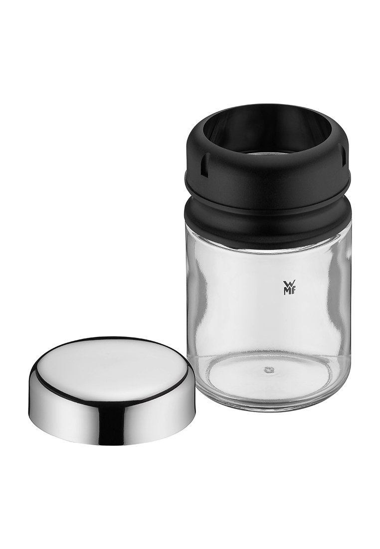Przezroczysty szklany pojemnik z czarną plastikową nakrętką usuniętą i umieszczoną obok, z widoczną srebrną zewnętrzną pokrywką po bokach.