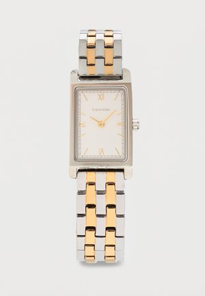 Montre-bracelet rectangulaire Calvin Klein en argent et or avec cadran blanc, chiffres romains dorés et bracelet métallique bicolore.