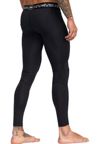 Sorte træningsleggings med en glat tekstur, der har en kontrasterende mærkebånd i taljen og syninger. Hud synlig på de nederste ben.