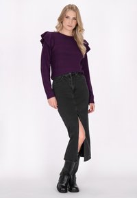 Paarse, gestructureerde lange mouw sweater met gerimpelde schouders, gecombineerd met een zwarte denim rok met een vooropening, aangevuld met zwarte kniehoog laarzen.