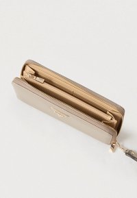 Bézs bőr pénztárca cipzáras záródással, sima textúrával, több kártyatartóval és aranyszínű díszítéssel. A belső része világosbarna.