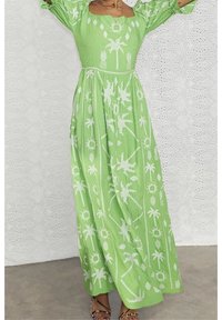 Maxiklänning i ljusgrön tyg med puffärmar, prydd med vita palmträd och solmönster, strukturerad yta och lös passform.