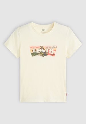 Kreminės spalvos medvilninė marškinė su trumpomis rankovėmis, puikuojanti spalvingu grafiniu logotipu, kuriame yra tekstas "Levi's" ir papildomi dizaino elementai.
