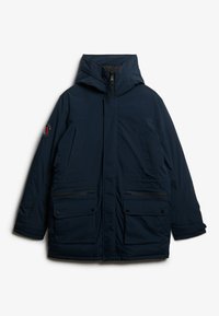 Parka matelassée bleu marine avec capuche, comportant plusieurs poches avant, des fermetures éclair et une texture lisse. Logo de la marque sur la manche.