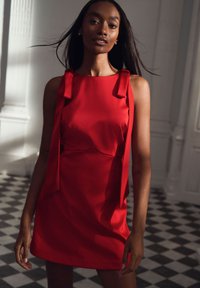 Červené mini šaty z hladké látky s mašlemi na ramenou, s přiléhavým střihem, jemnou texturou a lehce strukturovaným živůtkem.