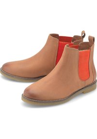 Paire de bottines Chelsea en cuir marron avec panneaux élastiques orange sur les côtés et semelles en caoutchouc clair, présentées de biais pour montrer les côtés intérieurs et les languettes de tirage.