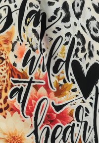 Stof met bloemen- en dierenprints in tinten crème, oranje, zwart en roze, met vette handgeschreven tekst: "Blijf Wild van Hart."