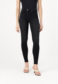 Sorte højtaljede skinny jeans med en glat tekstur og et tætsiddende design, der har sidelommer og en strømlinet silhuet.