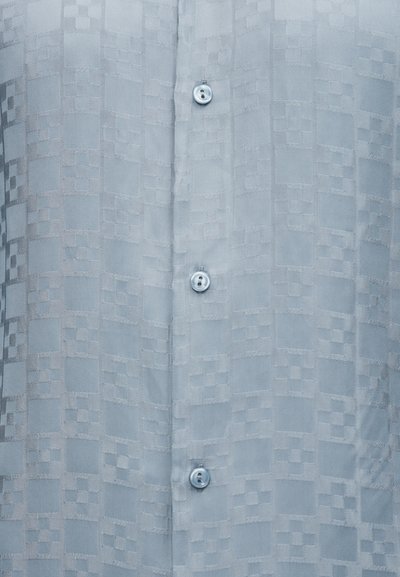 Ανοιχτό μπλε ύφασμα με διακριτικό καρό σχέδιο, που διαθέτει μία κάθετη σειρά από μικρά διαφανή κουμπιά.