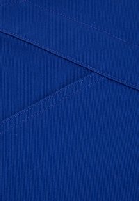 Blue fabric with a ribbed texture, featuring diagonal lines created by stitching. Smooth finish with contrasting thread accents.