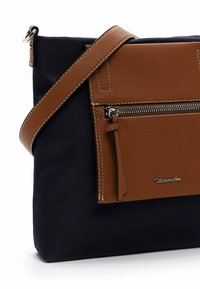 Borsa a tracolla in pelle marrone con tasca frontale testurizzata, corpo in tessuto blu navy, zip argentata e tracolla regolabile.