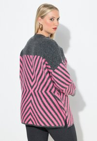 Grauer und rosa gemusterter Pullover mit Zickzackstreifen, einer weichen Textur und einer lockeren Passform, mit seitlichen Schlitzen für Bewegungsfreiheit.